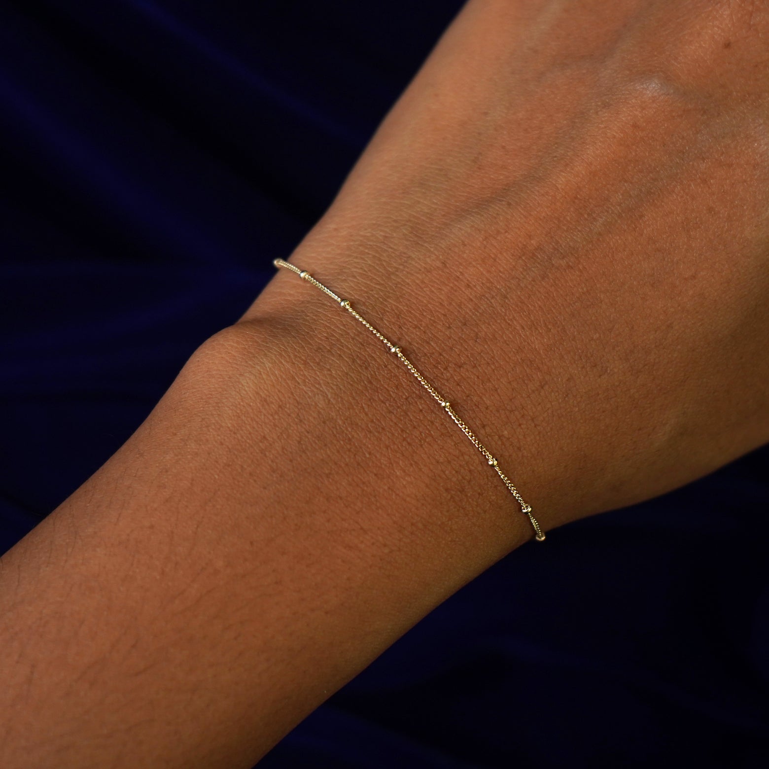 Close up view of a model's wrist wearing a yellow gold Beads Bracelet