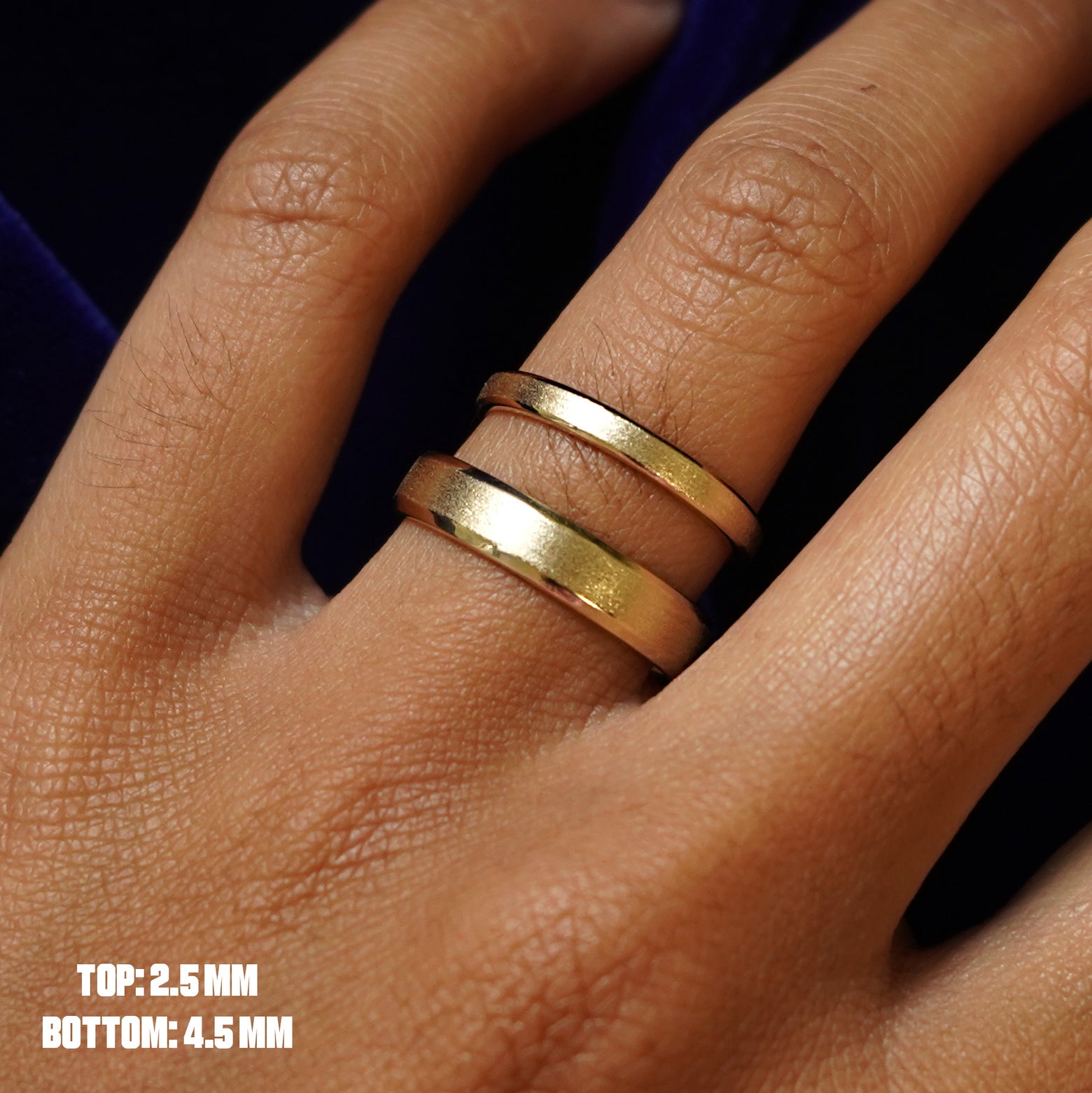 Close up view of a model's hand wearing a 2.5mm Beveled Edge Band and a 4.5mm Beveled Edge Band on the same finger