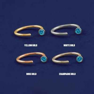 Four versions of the blue topaz Gemstone Open Hoop shown in options of yellow, white, rose and champagne gold