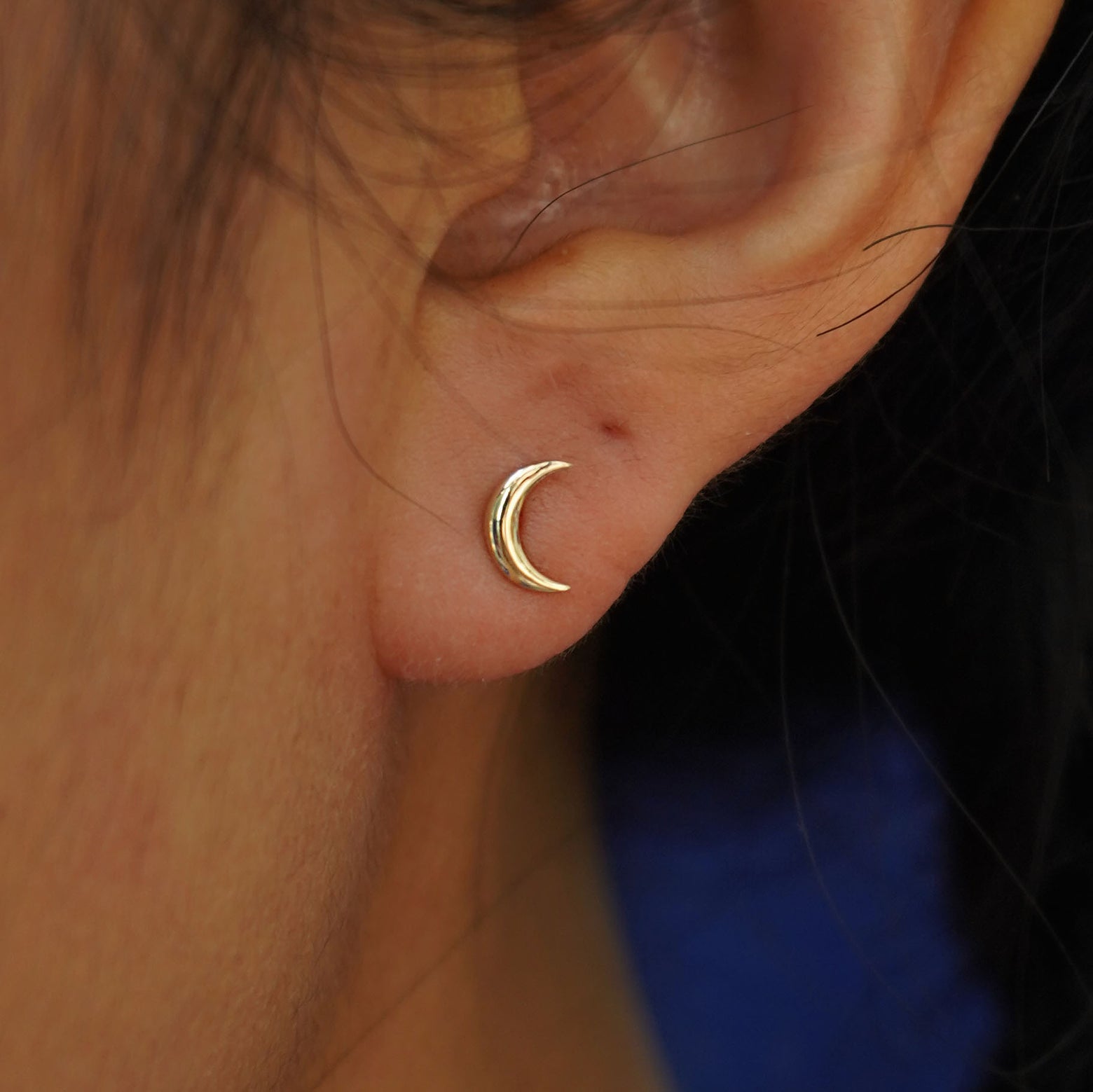 Close up view of a model's ear wearing a yellow gold Moon Earring