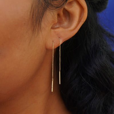 Close up view of a model's ear wearing a Threader through looped tightly in the back through two piercings and dangling