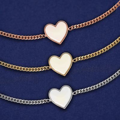 Three white enamel heart bracelets shown in options of rose, yellow, and white gold