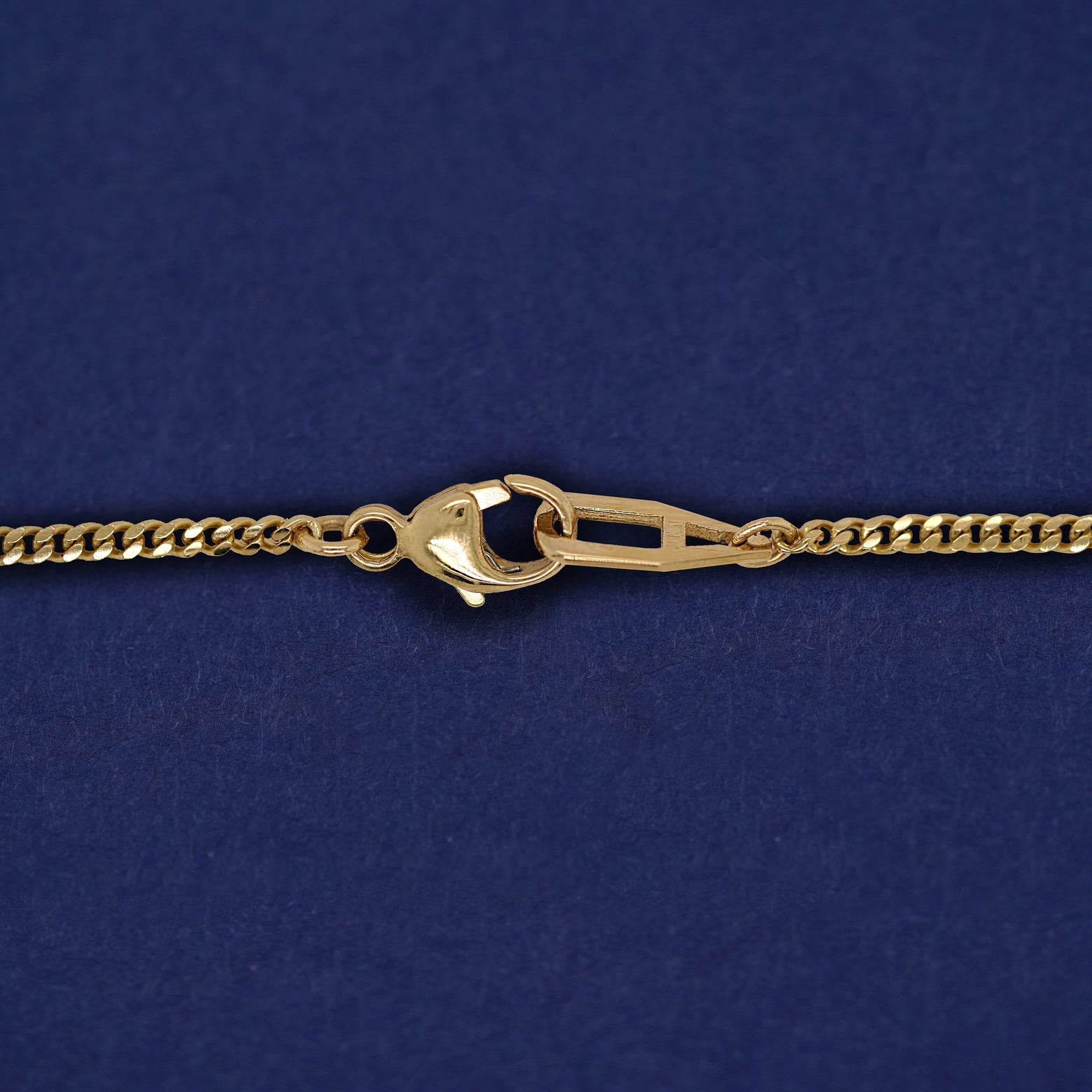 Close up view of a lobster lock and mini Miami chain on a yellow gold Enamel Heart Bracelet