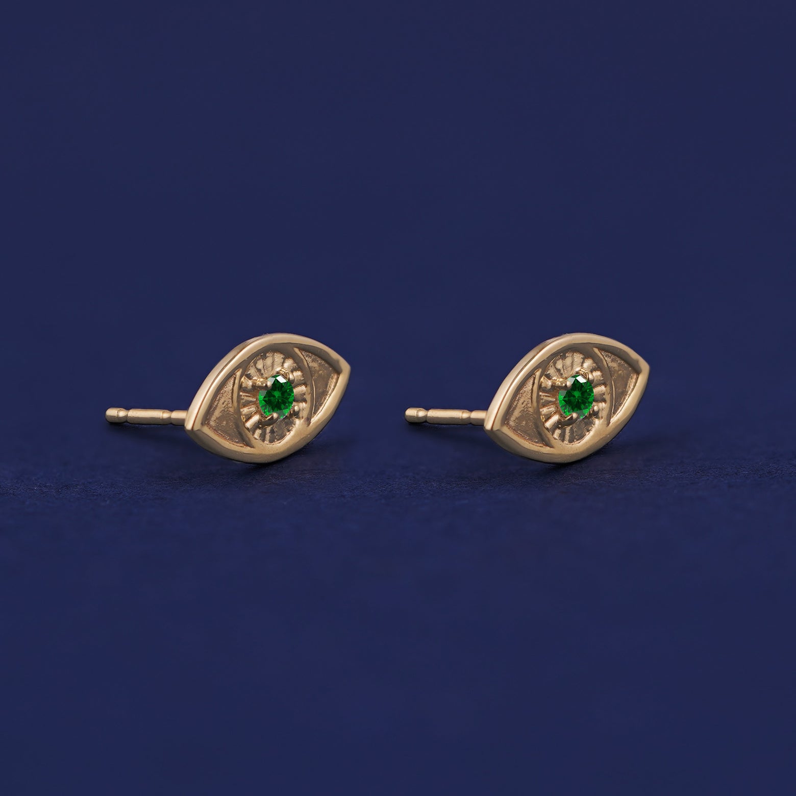 A pair of yellow gold emerald Evil Eye Earrings shown with pushback posts and no backings