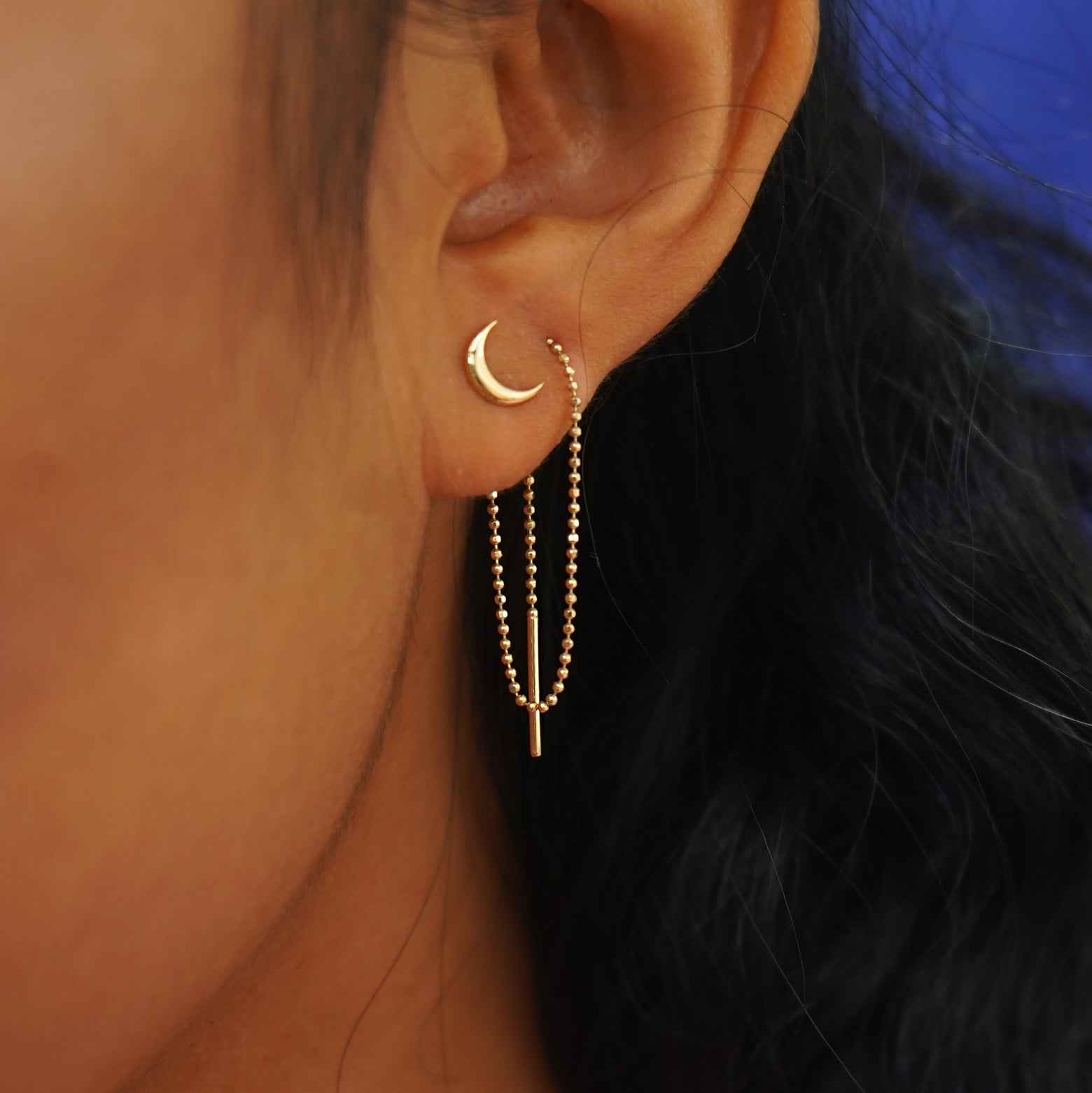 A model's ear wearing a Moon Earring with an Extender attached at the back and looped forward and through a second piercing