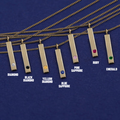 Seven versions of the Gemstone Bar Necklace showing all the gemstone options laid out on a dark blue background