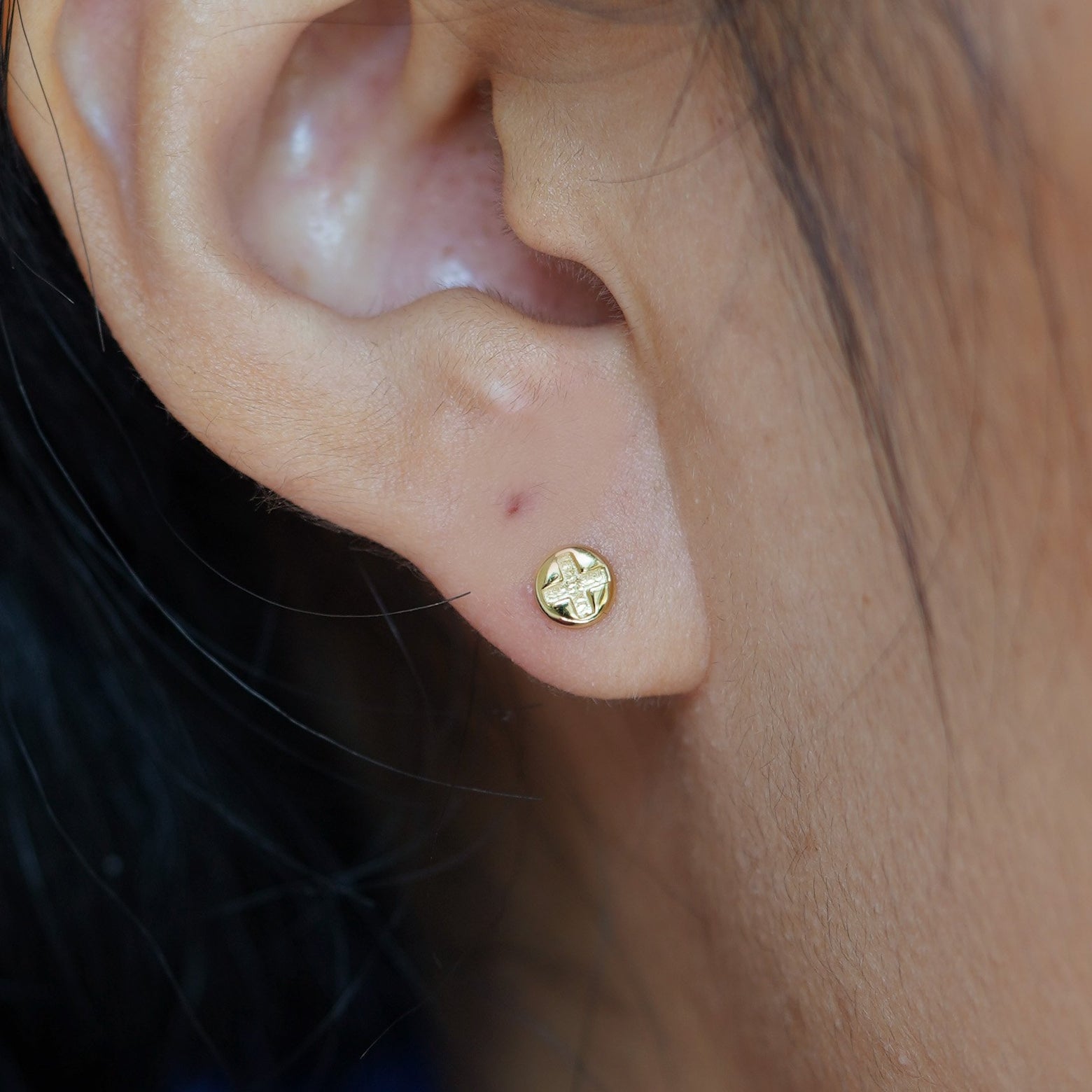 Close up view of a model's ear wearing a yellow gold Screw Flat Back Earring