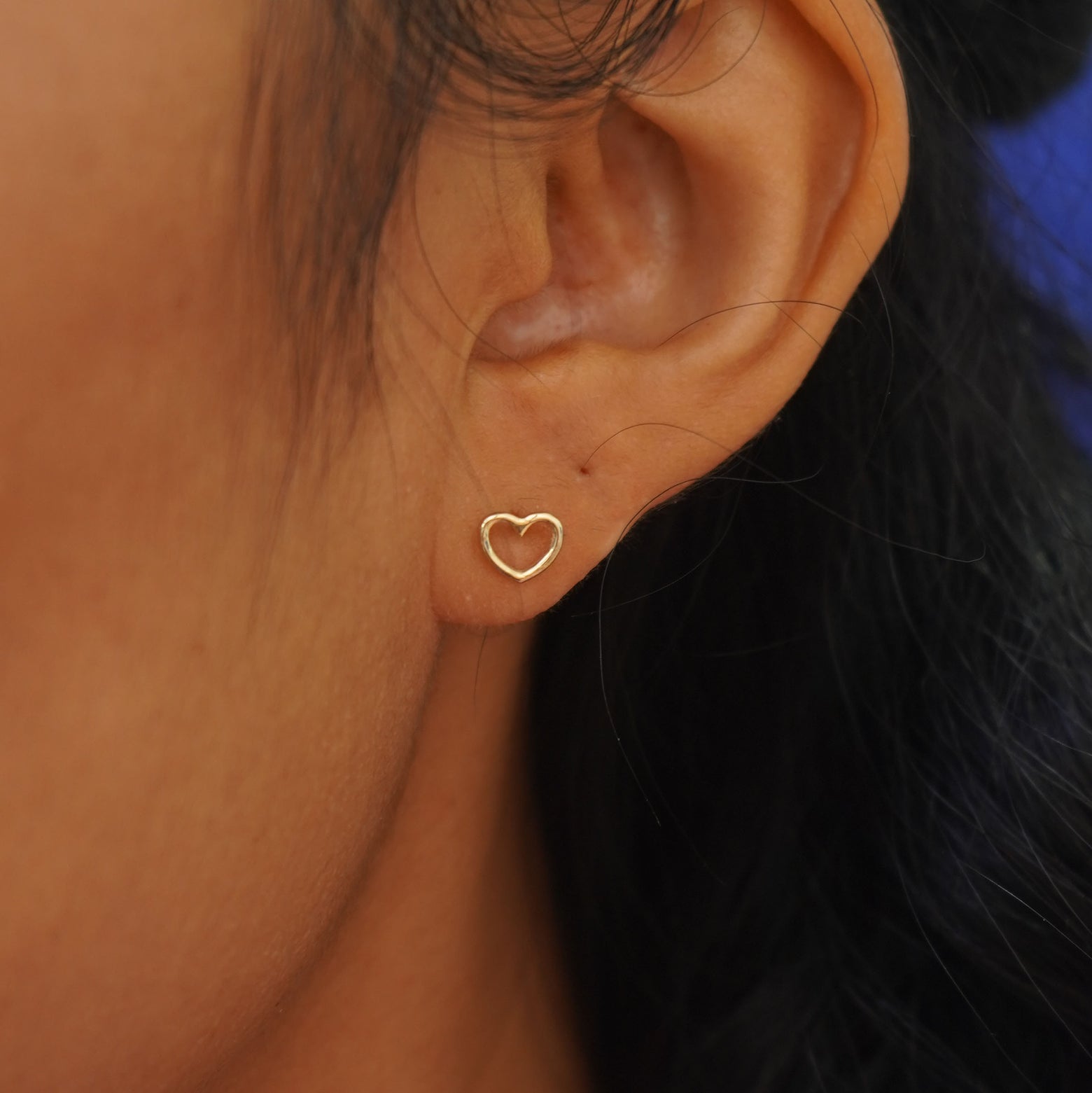 Close up view of a model's ear wearing a yellow gold Heart Earring