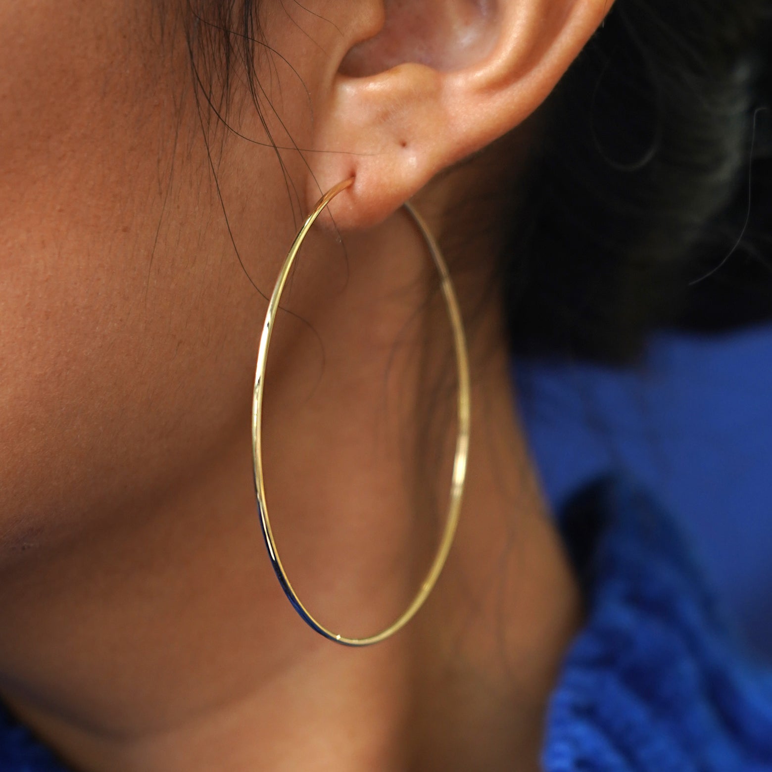 Close up view of a model's ear wearing a yellow gold Large Endless Hoop Earring