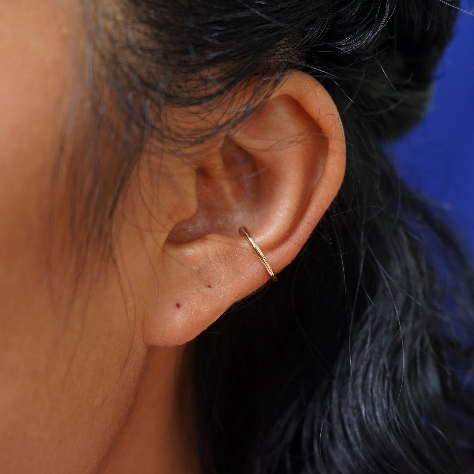 Close up view of a model's ear wearing a yellow gold Line Cuff