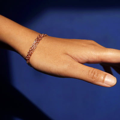 Close up view of a model wearing a 14k rose gold Wrap Necklace as a triple wrap bracelet