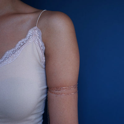 Close up view of a model wearing a 14k rose gold Wrap Necklace as a triple wrap arm band