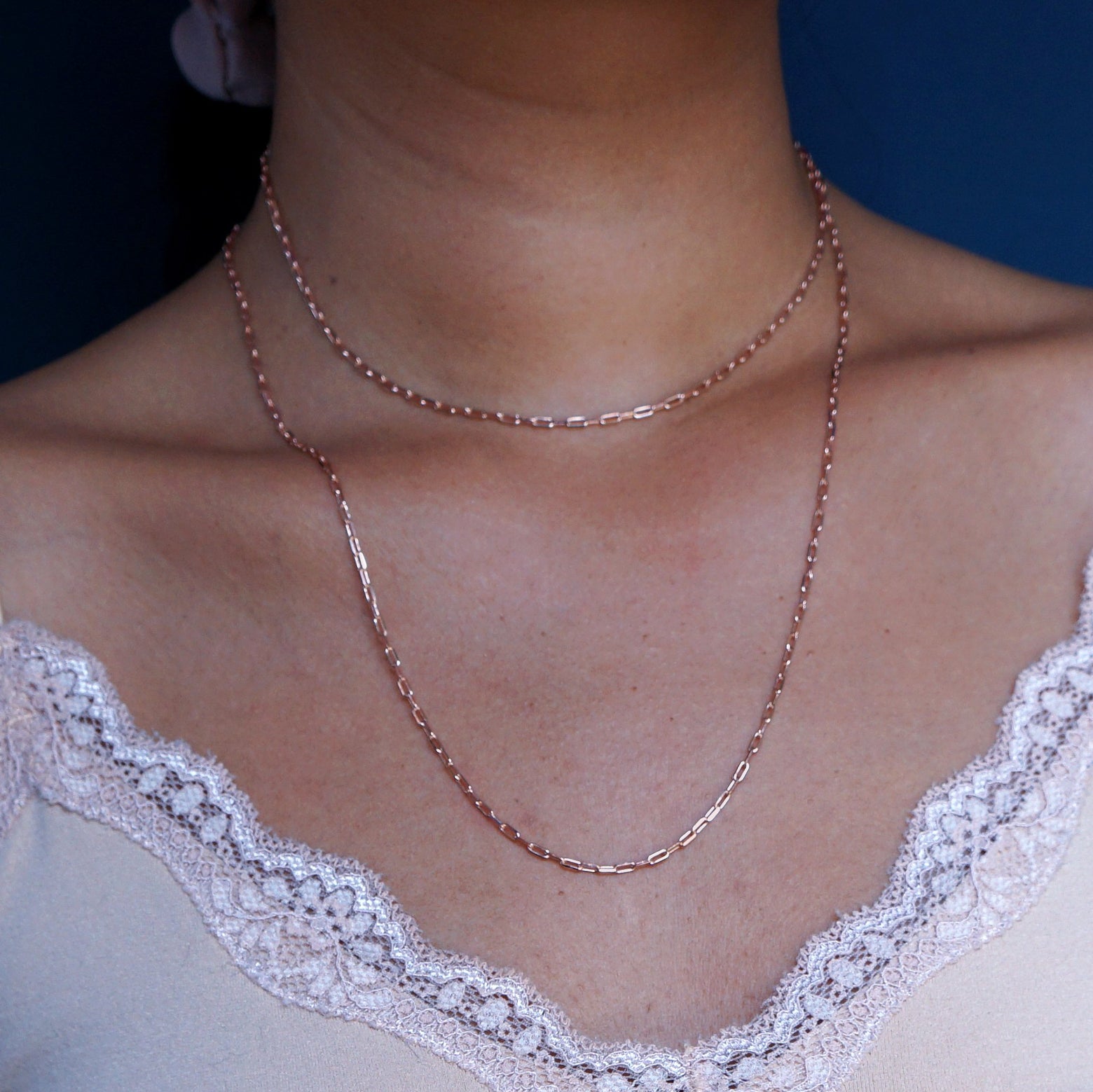 Close up view of a model wearing a 14k rose gold Wrap Necklace doubled as a collar necklace with a longer layer