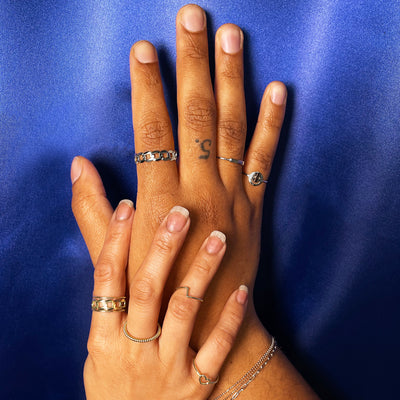 Two models' hands touching while one wears 14k white gold rings and the other wears 14k yellow gold rings