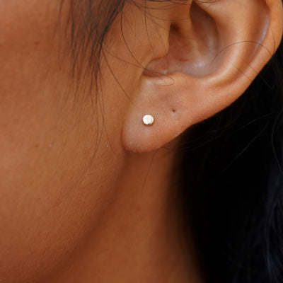 Close up view of a model's ear wearing a yellow gold Medium Flat Back Earring