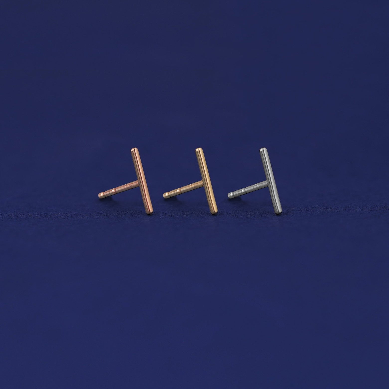 Three versions of the Medium Line Earring shown in options of rose, yellow, and white gold