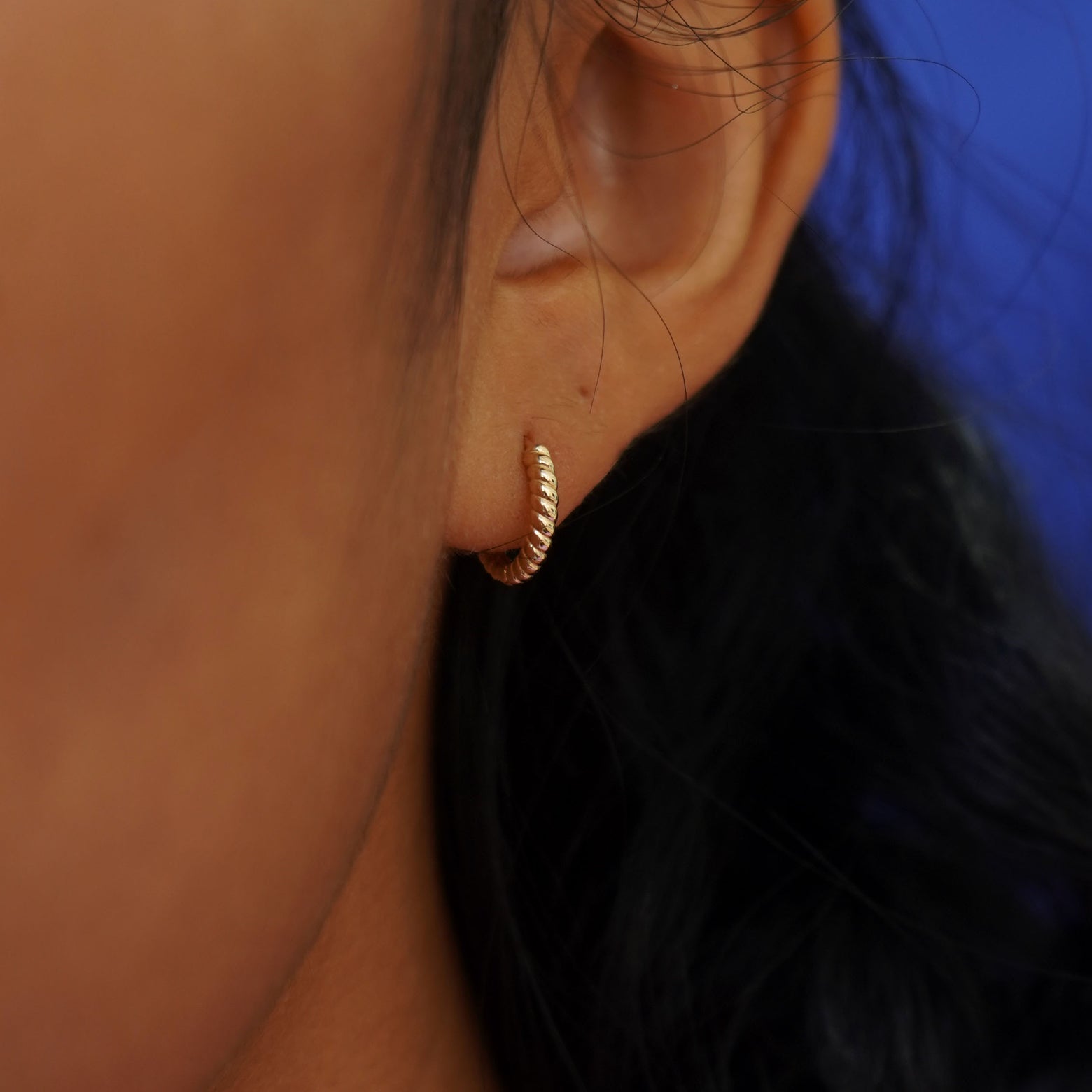 Close up view of a model's ear wearing a yellow gold Mini Rope Huggie Hoop