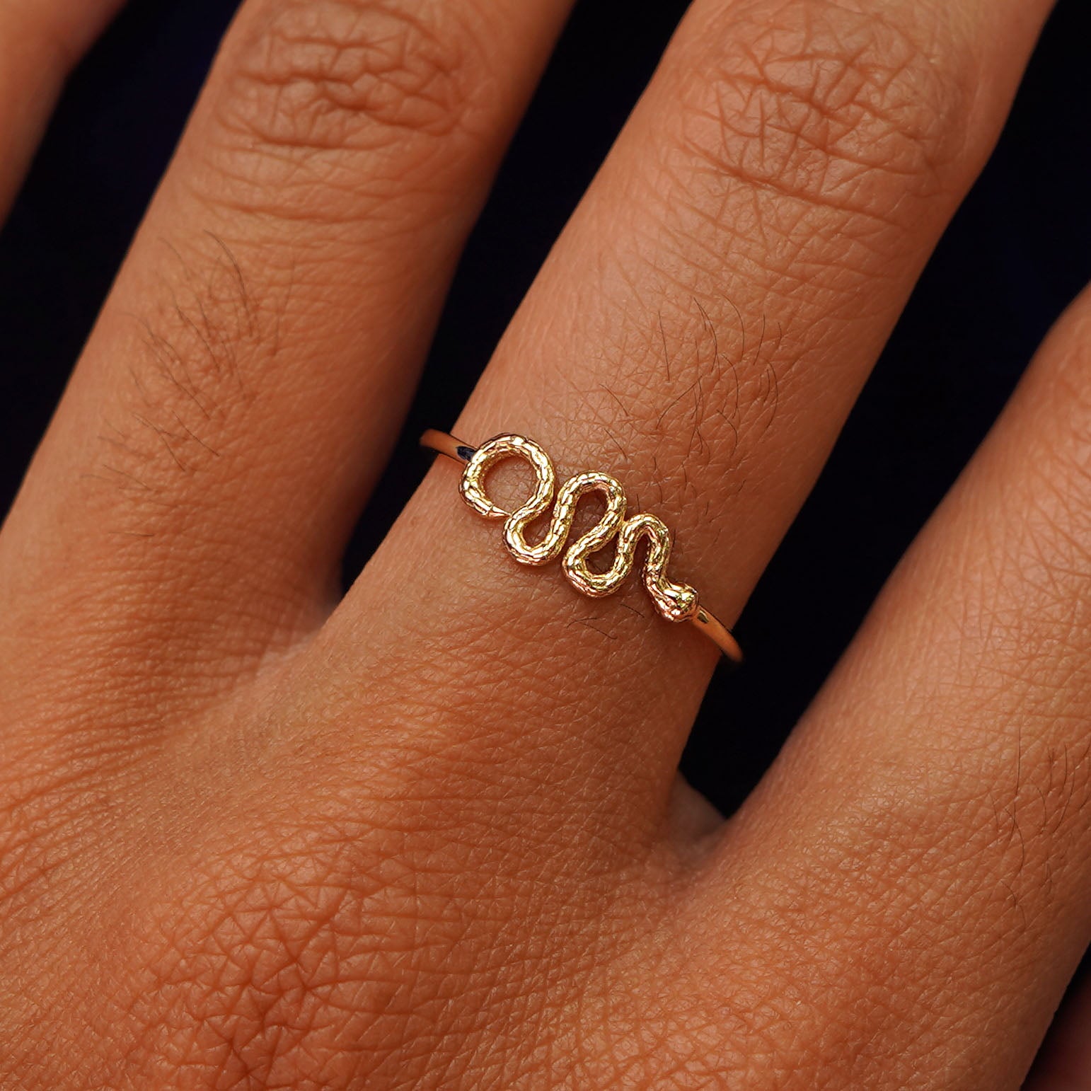 Close up view of a model's hand wearing a yellow gold Snake Ring