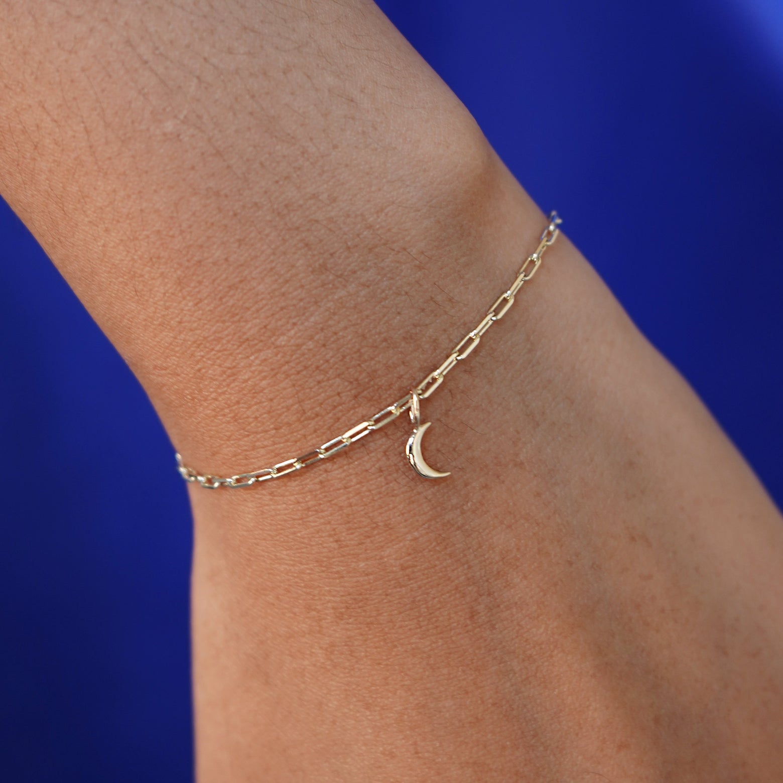 Close up view of a model's wrist wearing a yellow gold Moon Charm on a Butch Chain Bracelet