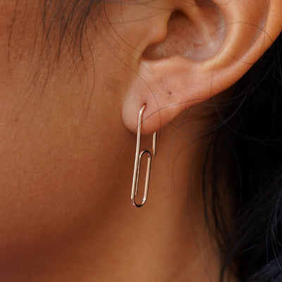 A model's ear wearing a 14k solid gold Not A Paper Clip Earring