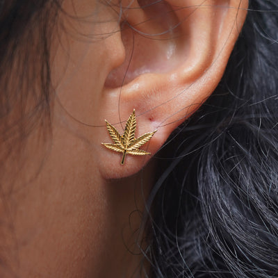 Close up view of a model's ear wearing a yellow gold Pot Leaf Earring