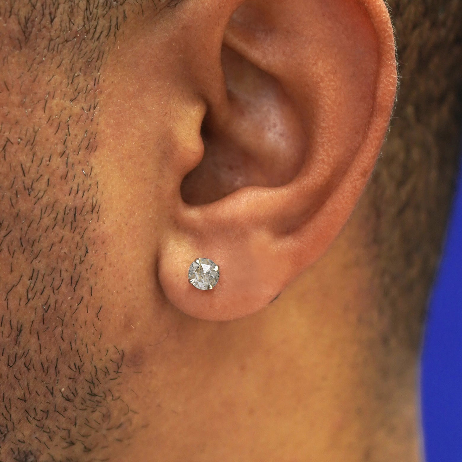 A model's ear wearing a solid 14k yellow gold salt and pepper diamond pressure lock earring