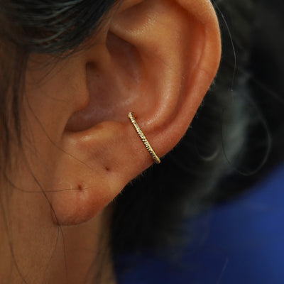 Close up view of a model's ear wearing a 14k yellow gold Shimmer Line Cuff