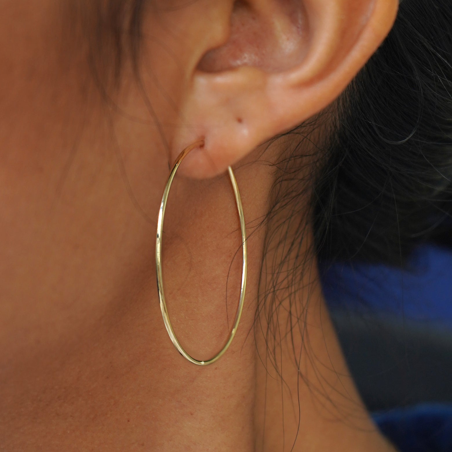 Close up view of a model's ear wearing a yellow gold Small Endless Hoop Earring