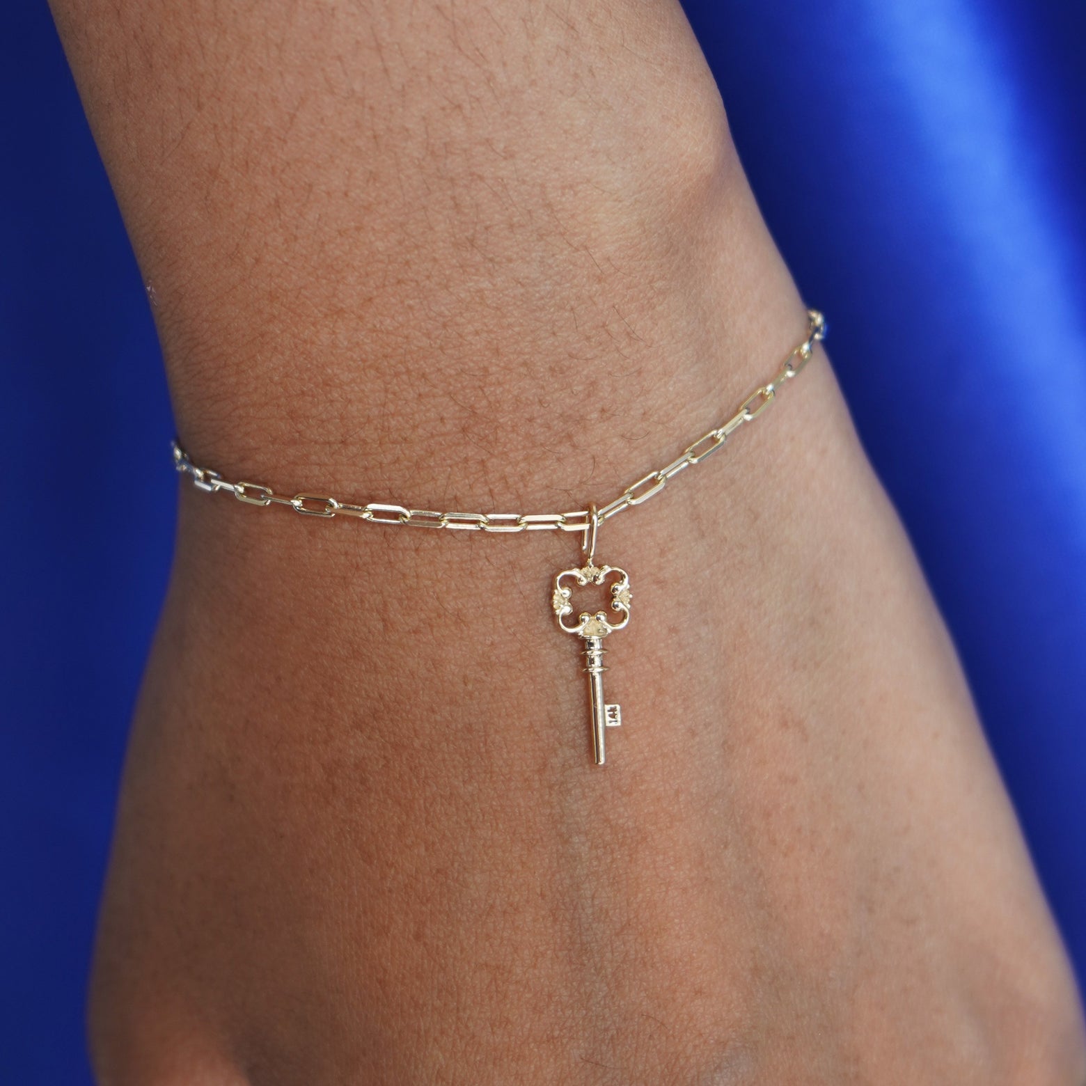 Close up view of a model's wrist wearing a yellow gold Key Charm on a Butch Bracelet