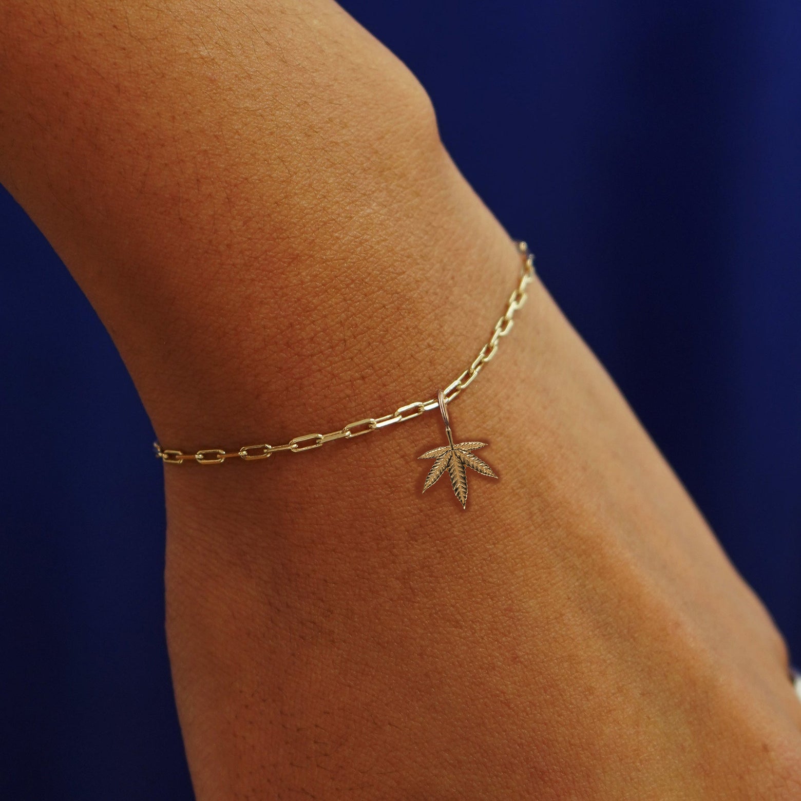 Close up view of a model's wrist wearing a yellow gold Cannabis Charm on a Butch Bracelet