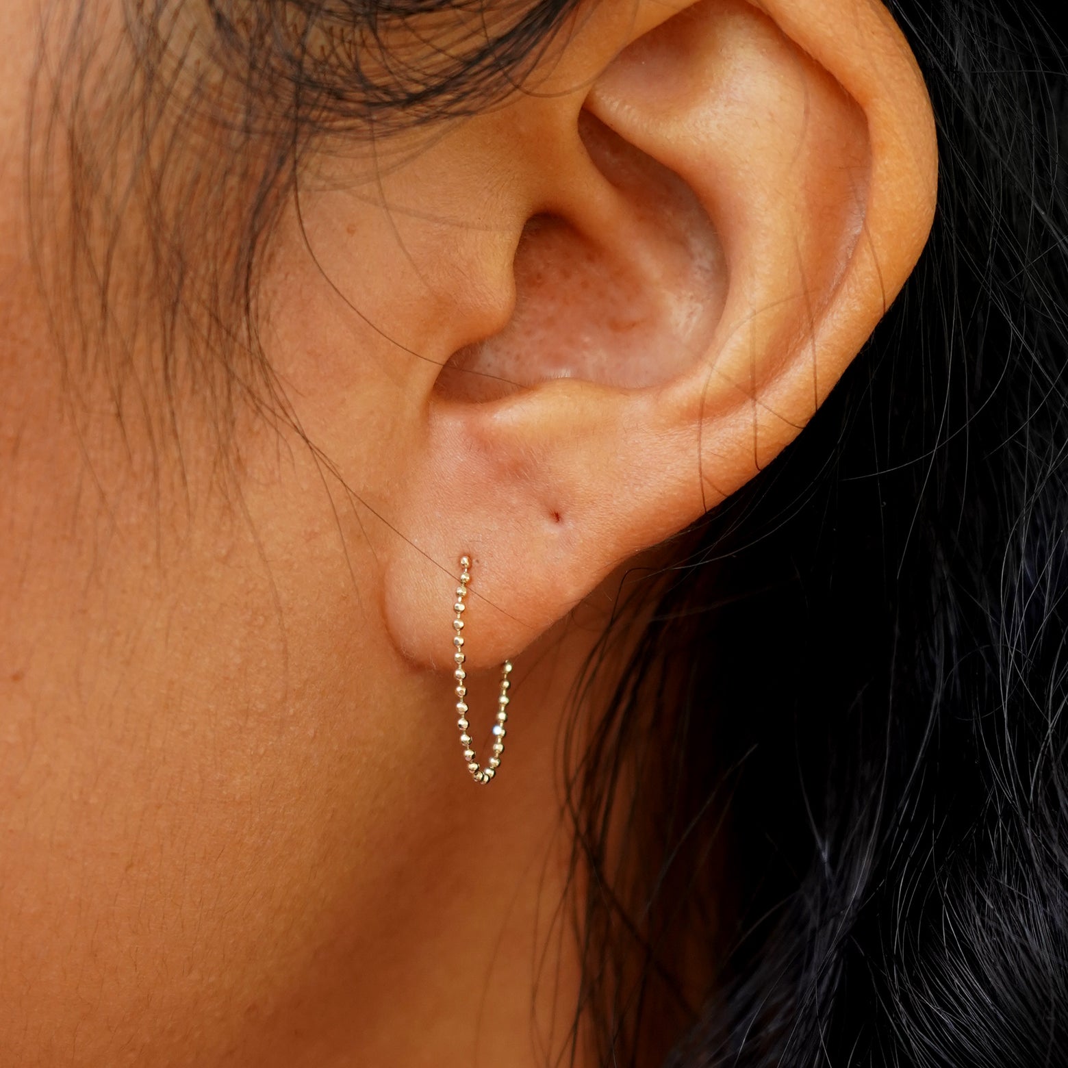 Close up view of a model's ear wearing a yellow gold Chain Loop Earring