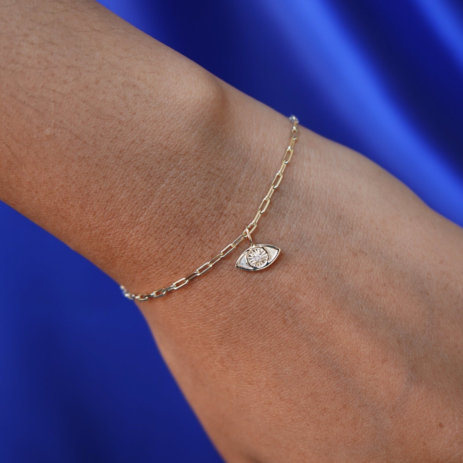 Close up view of a model's hand wearing a Diamond Evil Eye Charm on a yellow gold Butch Bracelet
