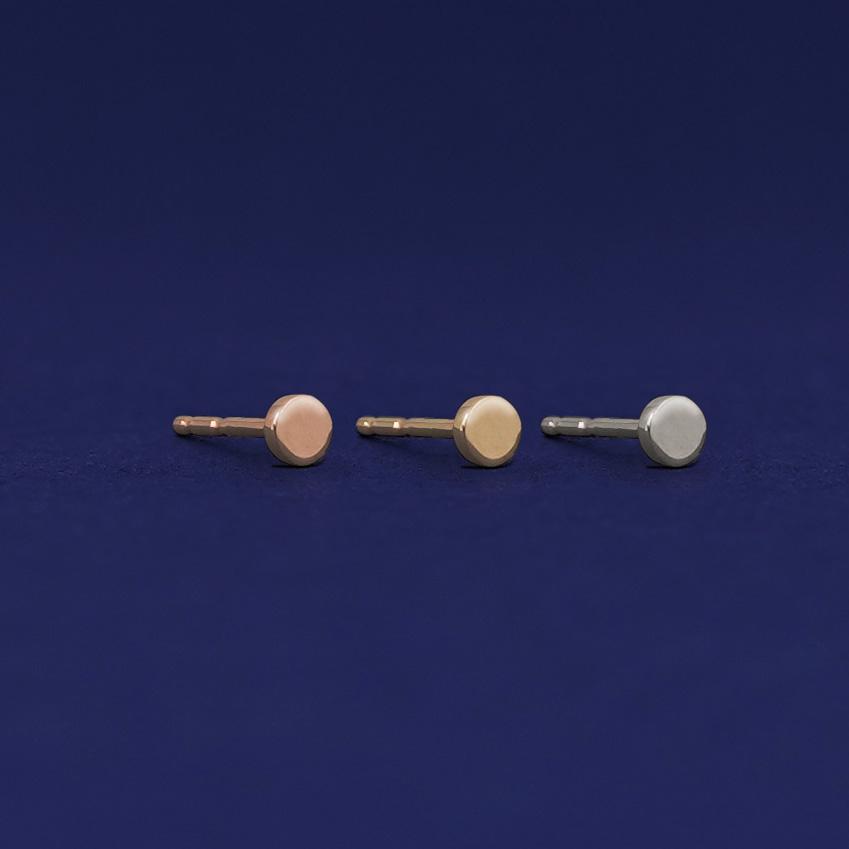 Three versions of the Teeny Tiny Circle Earring shown in options of rose, yellow, and white gold