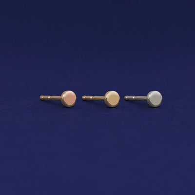 Three versions of the Teeny Tiny Circle Earring shown in options of rose, yellow, and white gold