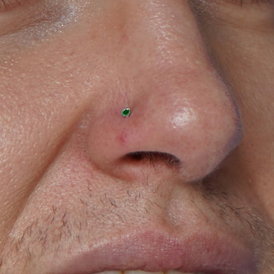 A model's nose wearing a 14 karat gold emerald Nose Stud