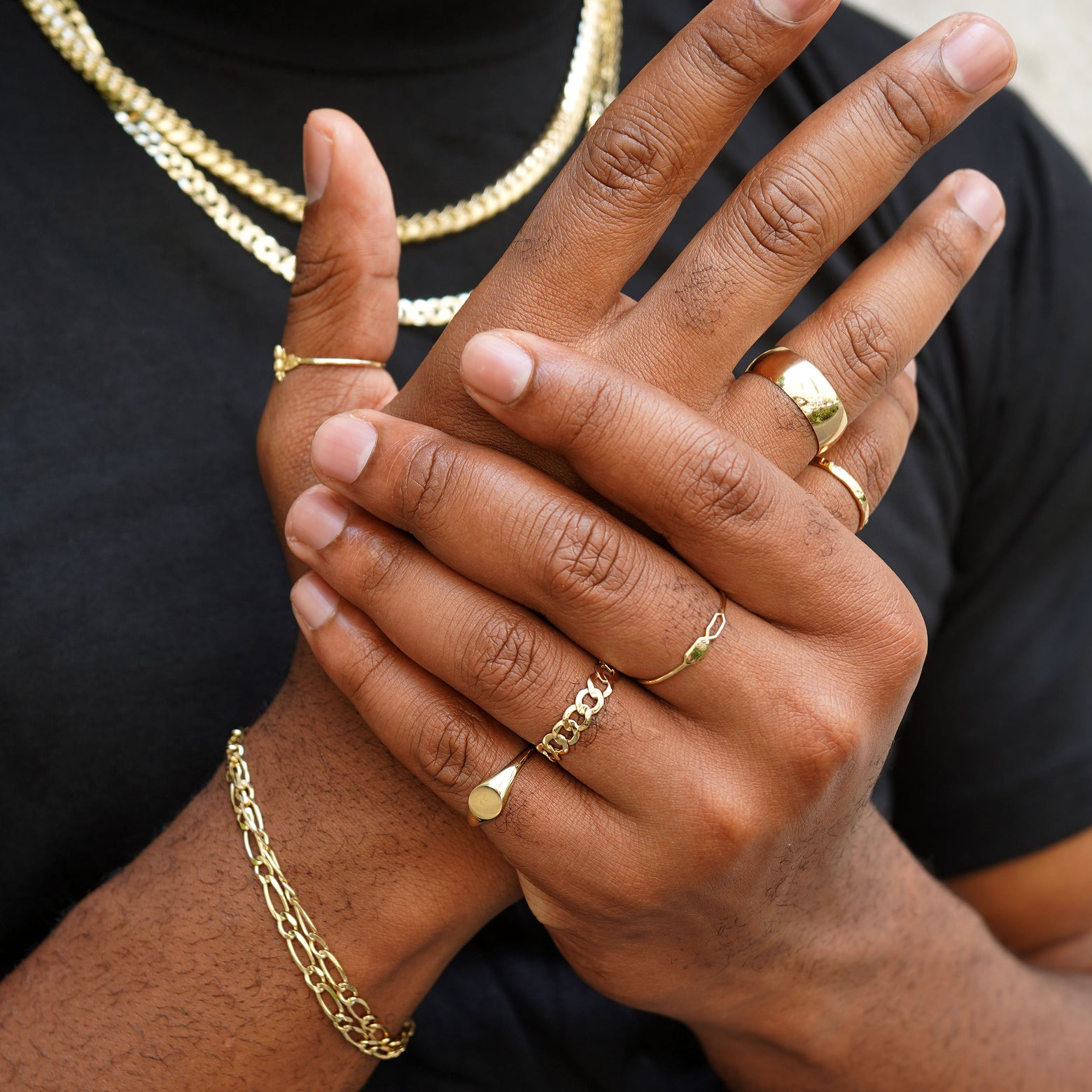A model with gently grasping their own palm wearing Automic Gold rings and chains