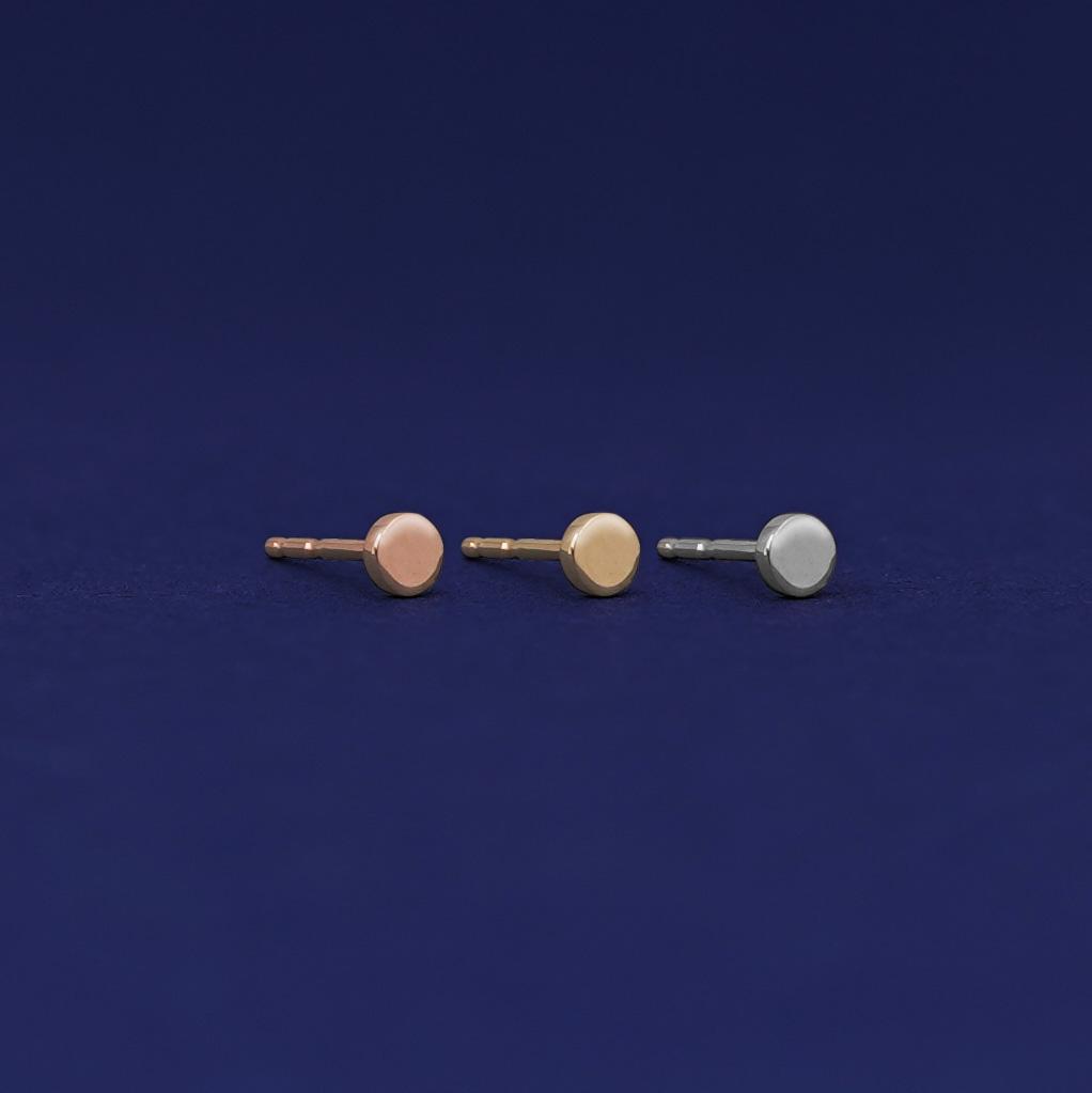 Three versions of the Tiny Circle Earring shown in options of rose, yellow, and white gold