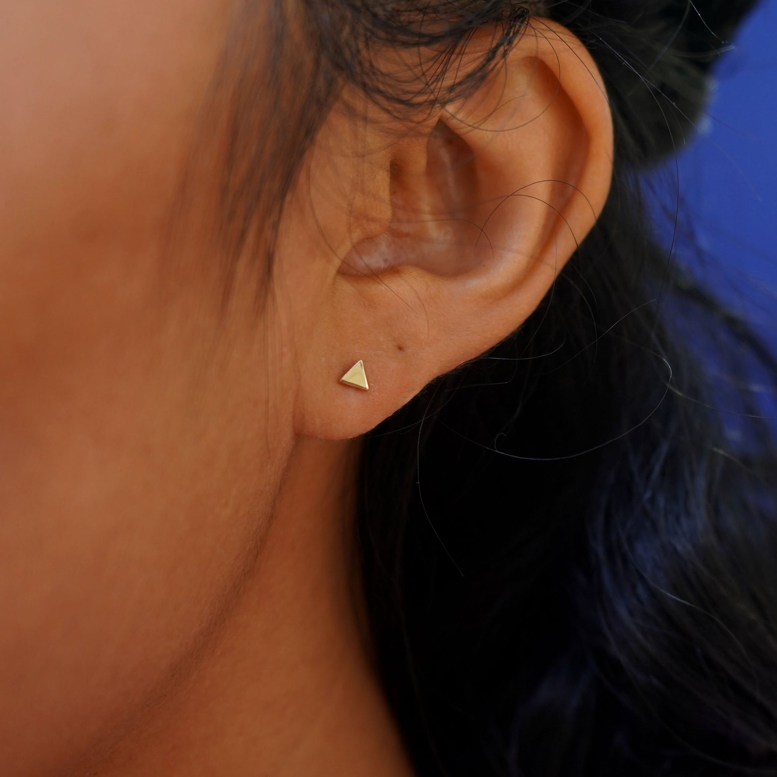 Close up view of a model's ear wearing a yellow gold Triangle Earring