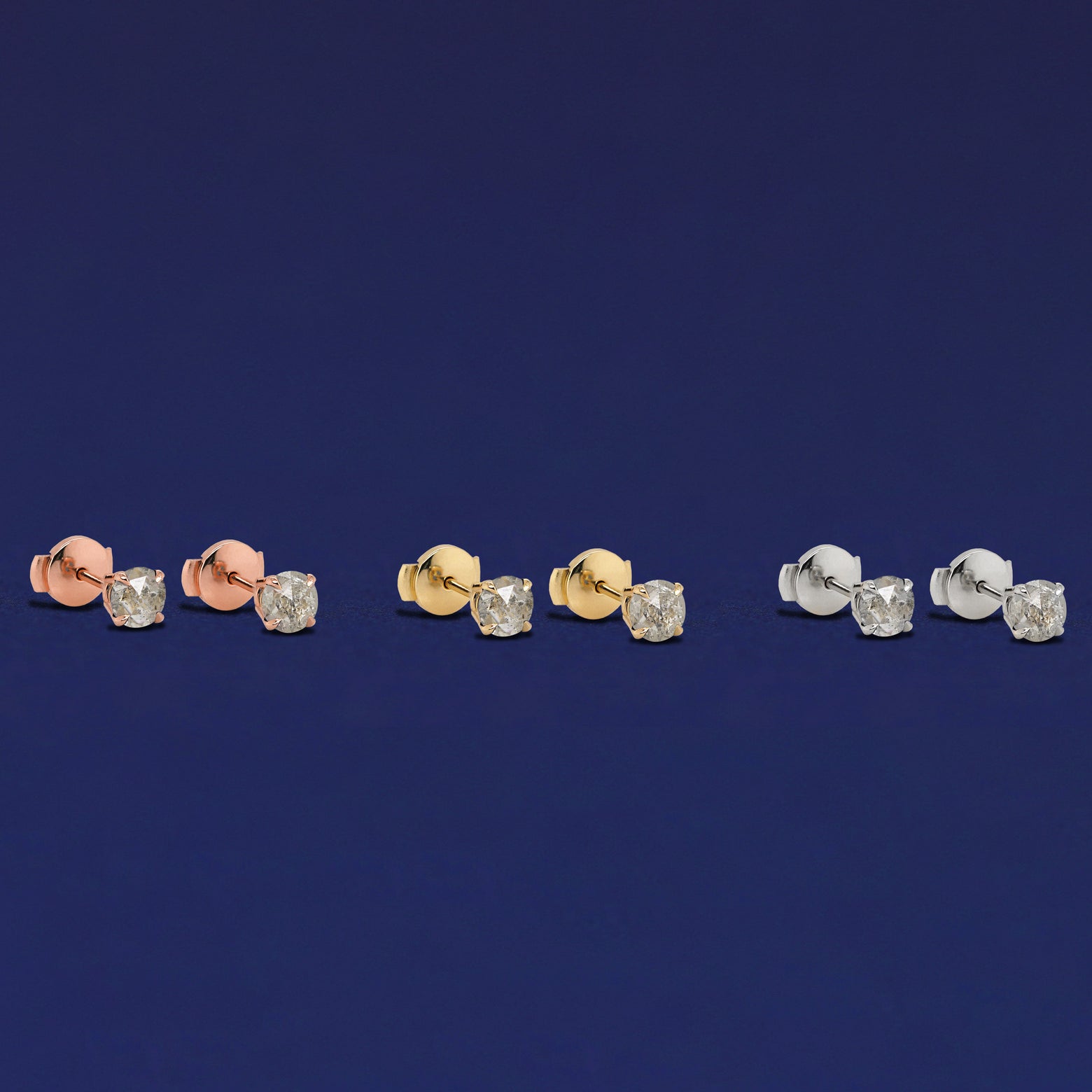 Three pairs of salt and pepper diamond pressure lock earrings shown in options of rose, yellow, and white gold