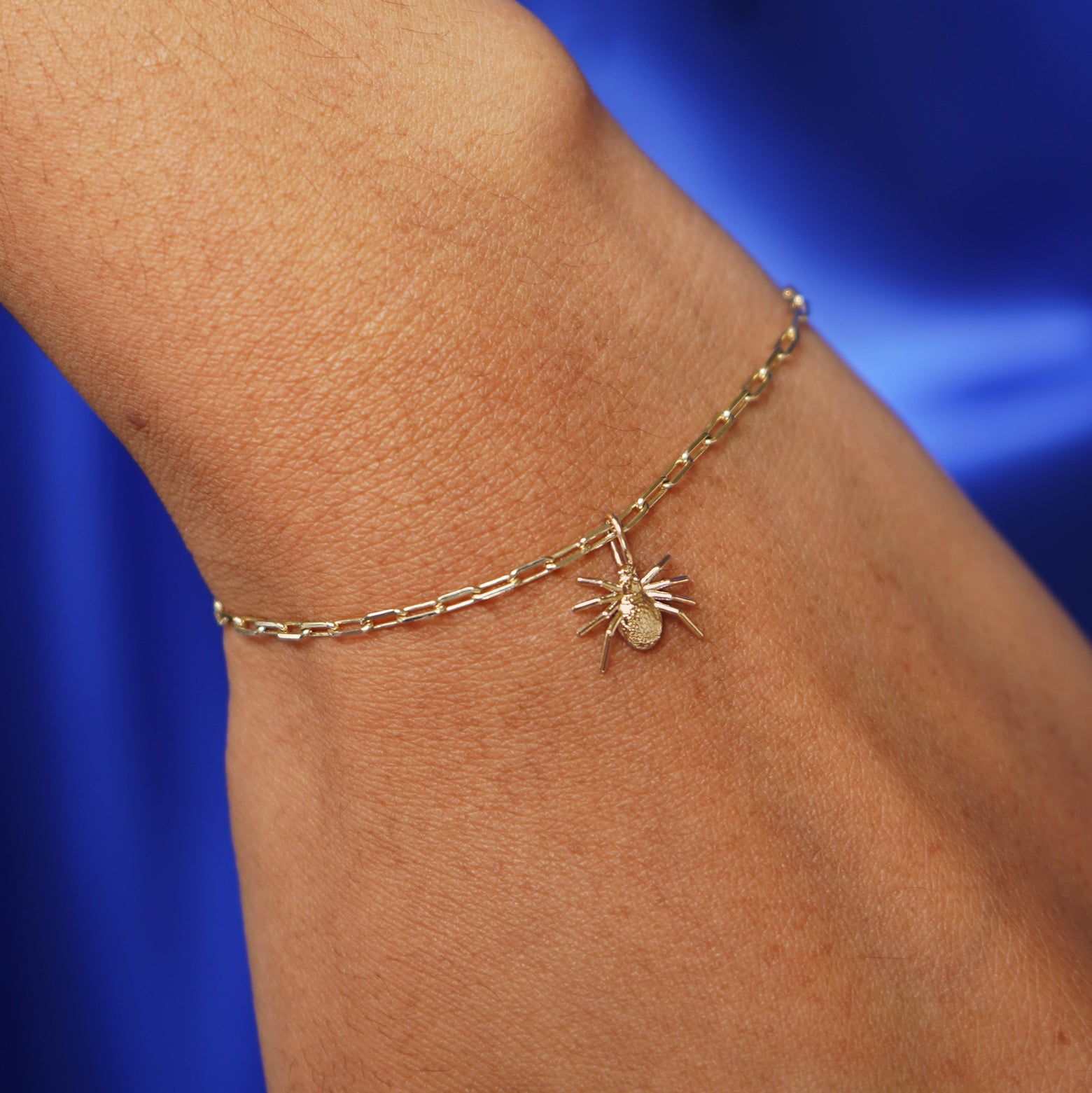 Close up view of a model's wrist wearing a yellow gold Spider Charm on a Butch Chain Bracelet