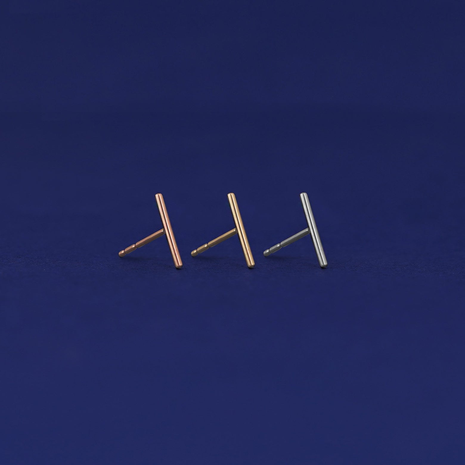 Three versions of the Tall Line Earring shown in options of rose, yellow, and white gold