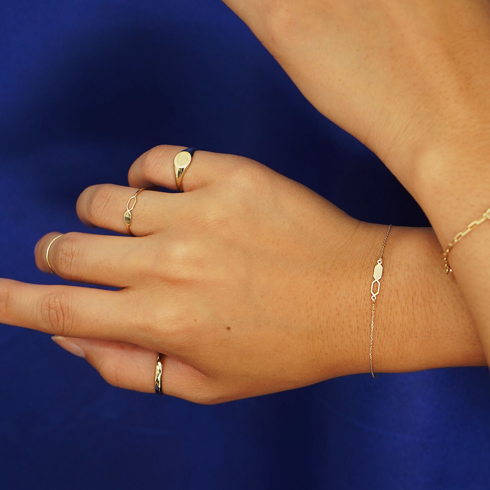 A model posing with their wrists crossed wearing a Tanlah Ring and other 14k solid gold jewelry