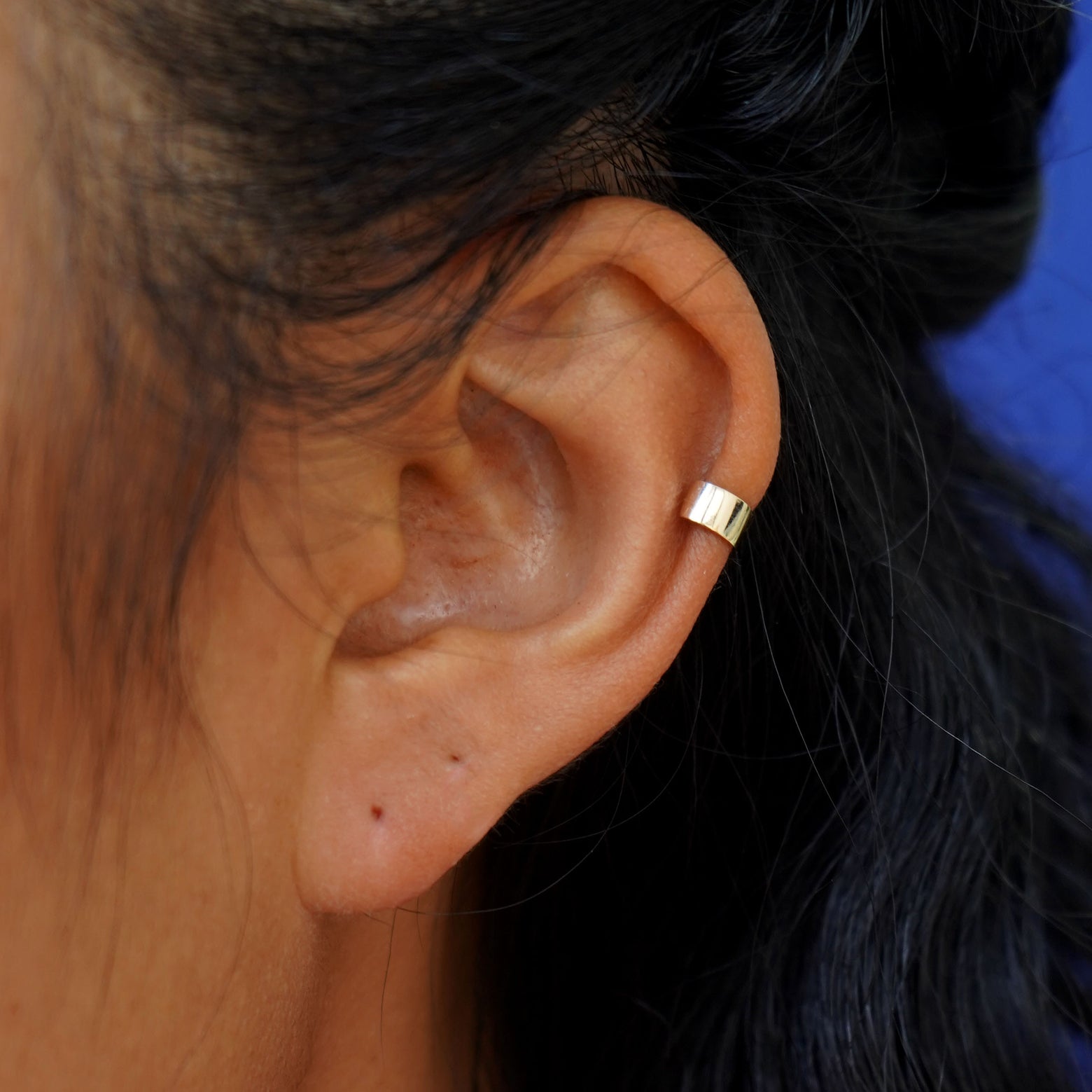 A model's ear wearing a 14k yellow gold Thick Cuff