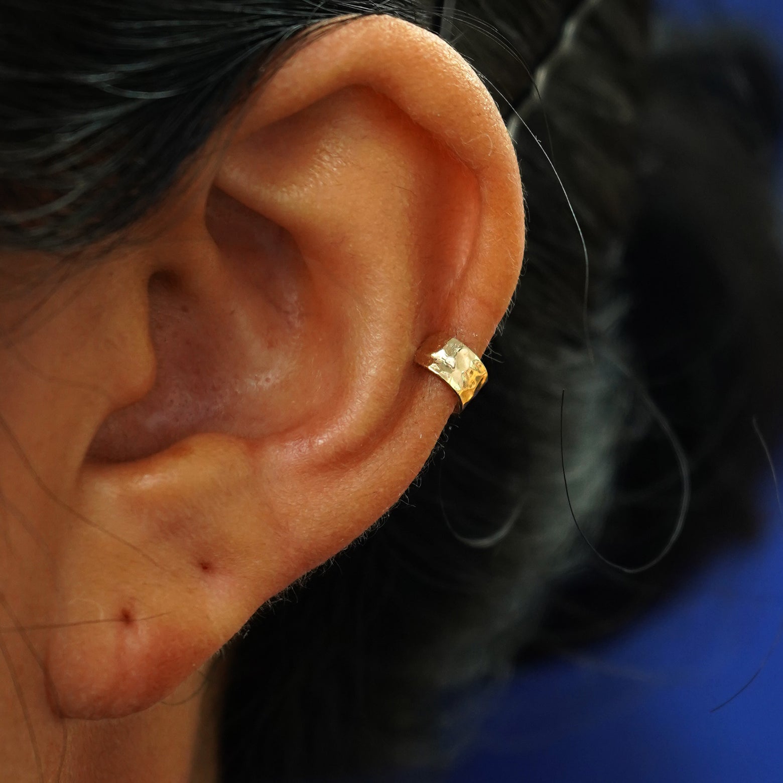 A model's ear wearing a 14k yellow gold Hammered Thick Cuff