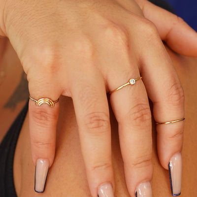 A model with long nails touching their shoulder while wearing a Diamond Ring, a Line Ring and a Rainbow Ring