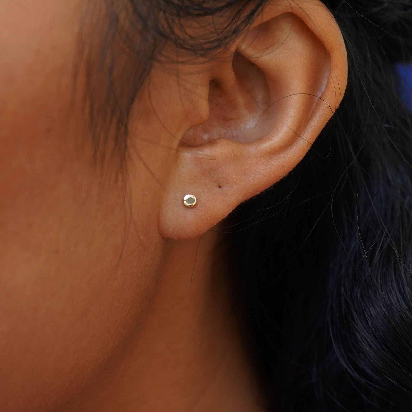 Close up view of a model's ear wearing a yellow gold Tiny Flat Back Earring