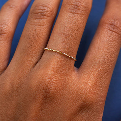 Close up view of a model's hand wearing a yellow gold Bead Chain Ring