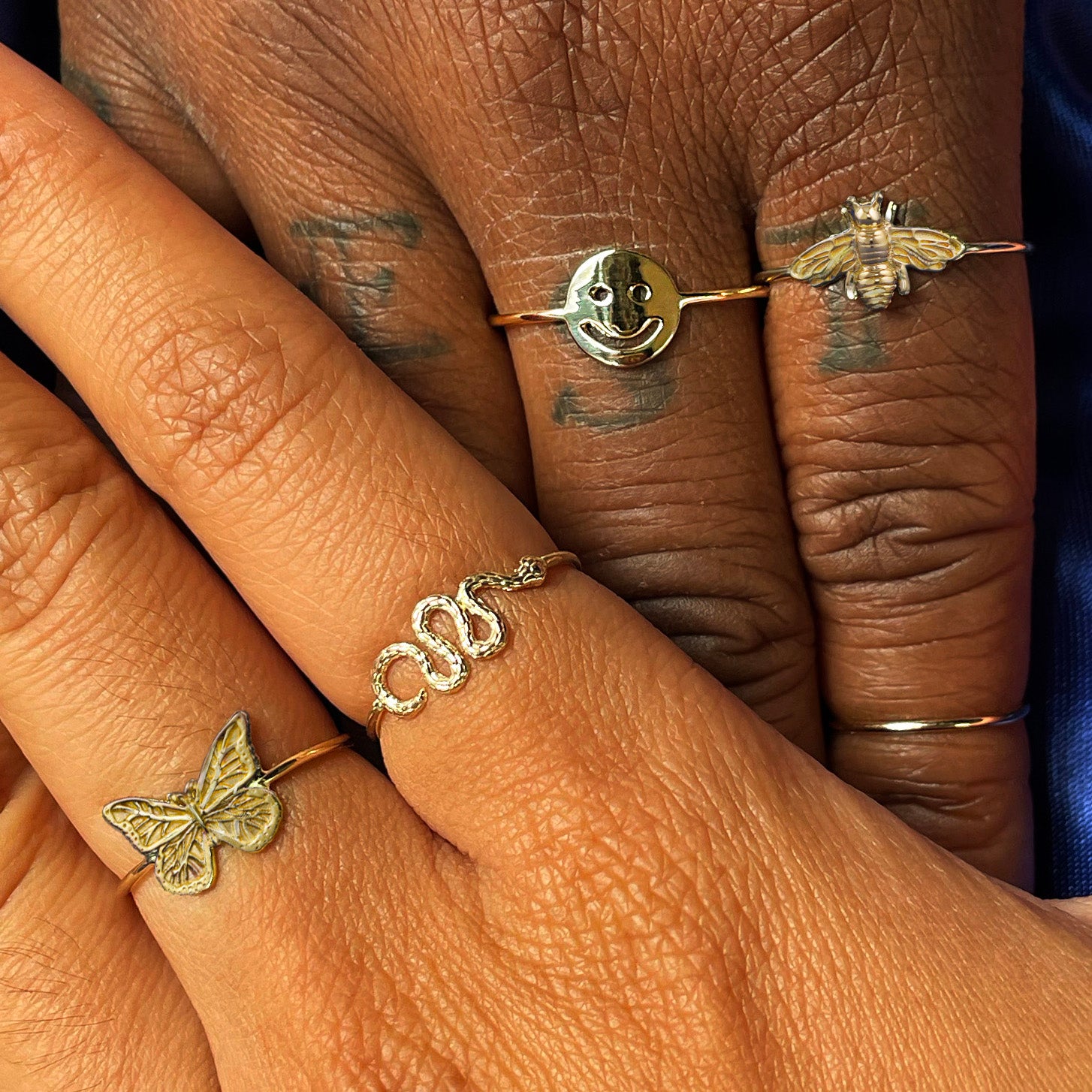 Two model's holding hands while wearing various Automic Gold rings