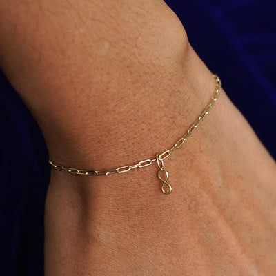 Close up view of a model's wrist wearing a yellow gold Infinity Charm on a Butch Bracelet
